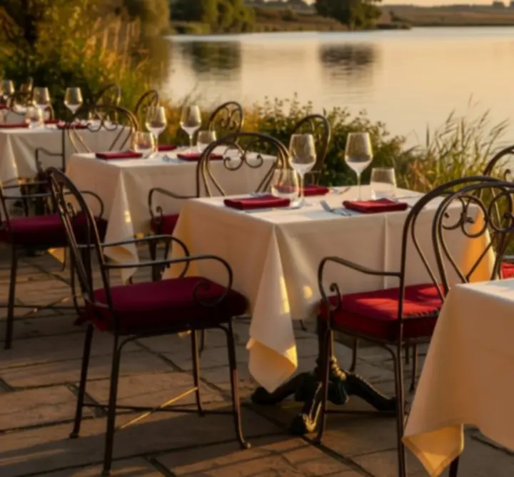 Riverside terrace with guests dining beside the Norfolk Broads at sunset